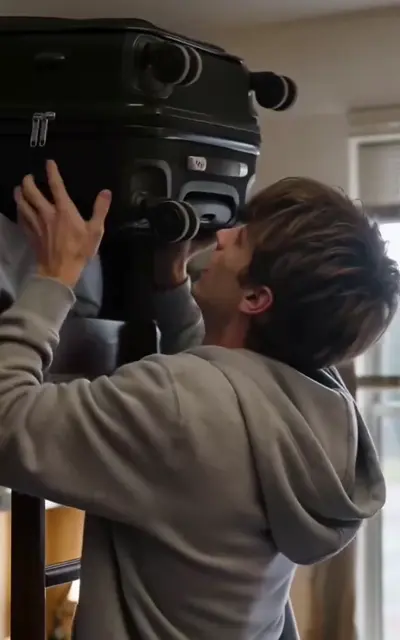 Miles lifts the heavy suitcase on the ladder