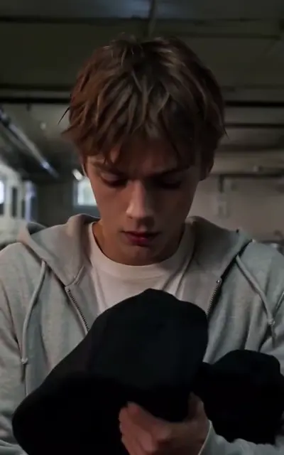 Miles holds the folded black hoodie in the dorm