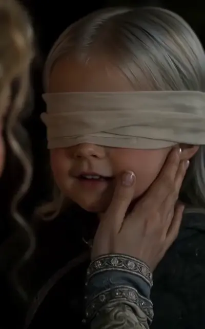 The mother holds the blindfolded child's cheek