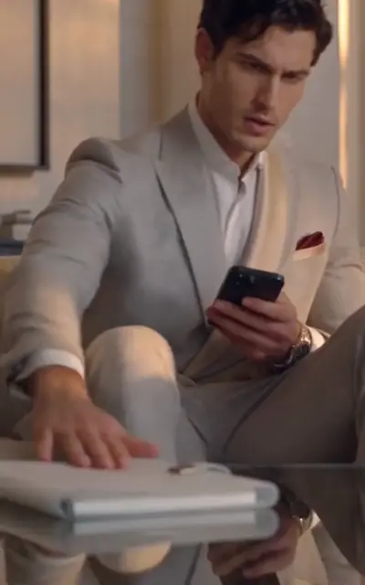 Evan sits looking at his phone in the light suit