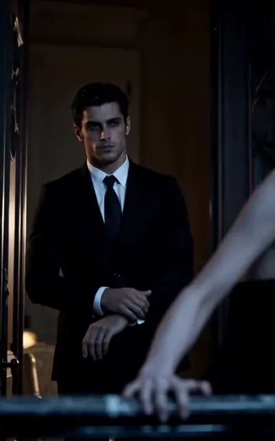 Julian standing in the dark doorway in a suit