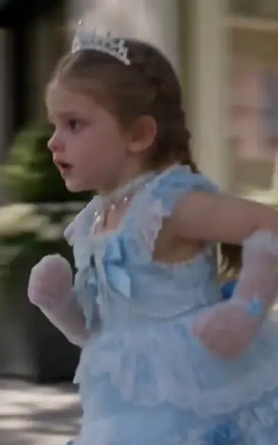 Rosie in a blue dress and tiara, fist raised