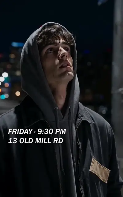 The clerk in a hooded coat under the city sign for 13 Old Mill Road