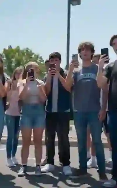 Students filming with phones in the school lot